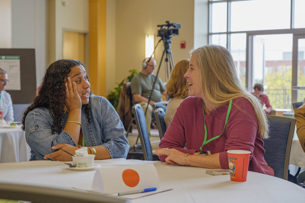 Two attendees having a lively conversation at the 2025 Summit
